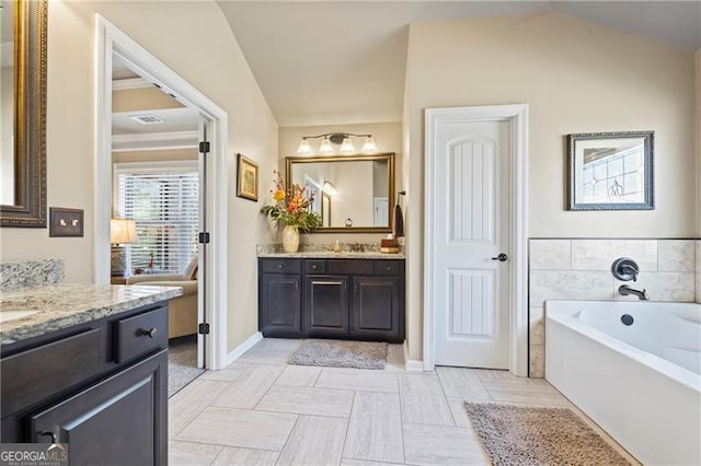 bathroom with a washtub, vanity, vaulted ceiling, and tile patterned flooring