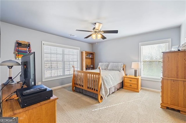 bedroom with ceiling fan, light carpet, and multiple windows