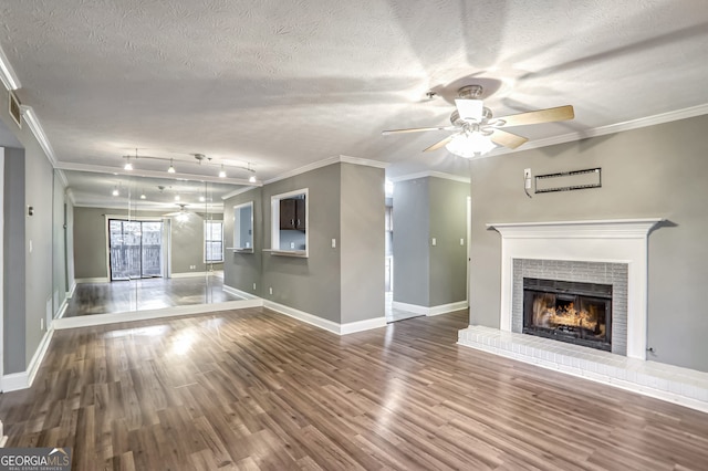 unfurnished living room featuring ceiling fan, crown molding, wood-type flooring, a textured ceiling, and a fireplace