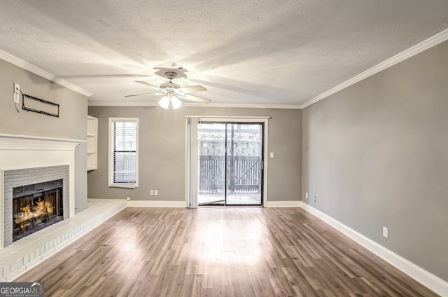 unfurnished living room with hardwood / wood-style floors, ceiling fan, ornamental molding, a fireplace, and a textured ceiling