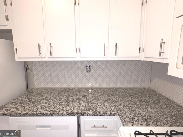 room details featuring white cabinets, decorative backsplash, dark stone countertops, and white dishwasher