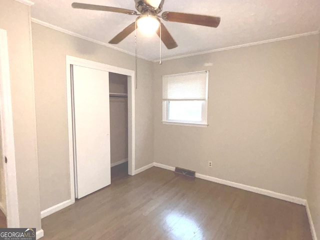 unfurnished bedroom with a closet, ceiling fan, crown molding, and hardwood / wood-style flooring