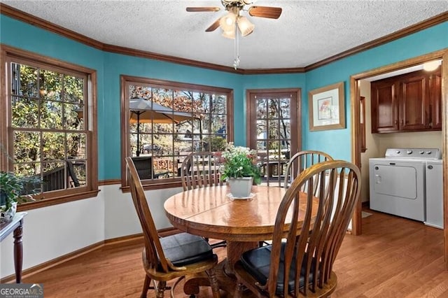 dining room featuring light wood-type flooring, washing machine and dryer, plenty of natural light, and crown molding