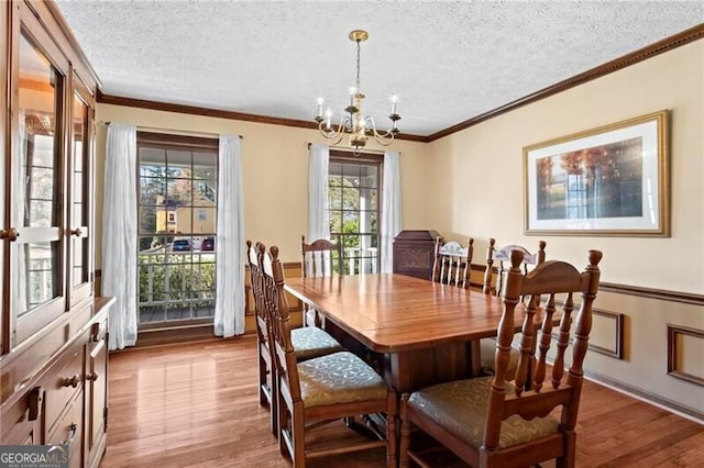 dining area with a healthy amount of sunlight, a chandelier, a textured ceiling, and light wood-type flooring