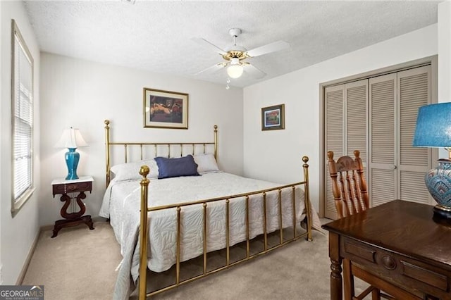 carpeted bedroom featuring ceiling fan, a closet, and a textured ceiling