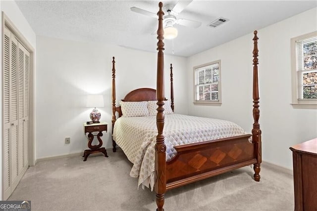 carpeted bedroom featuring multiple windows, ceiling fan, and a closet