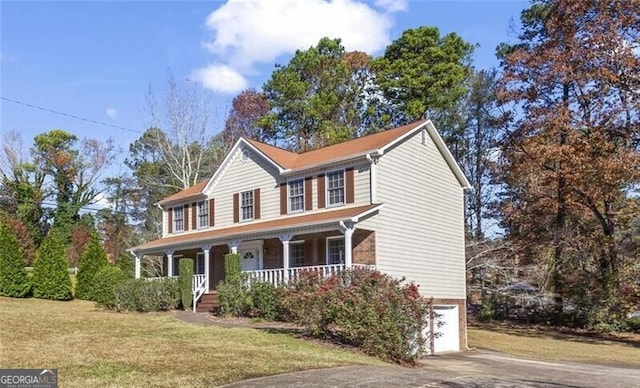 colonial house featuring a front lawn, covered porch, and a garage