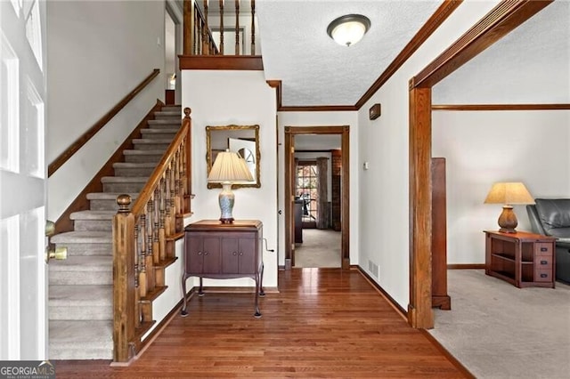 entrance foyer featuring wood-type flooring, a textured ceiling, and ornamental molding