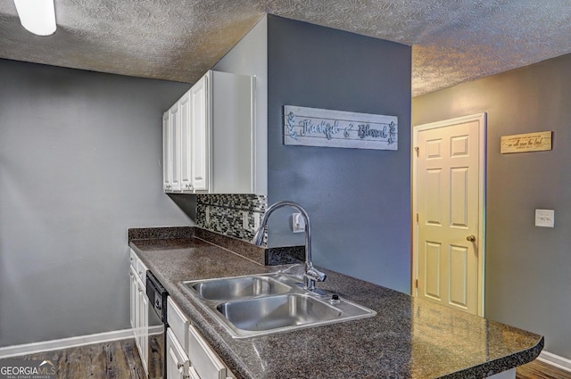 kitchen featuring dishwasher, sink, dark wood-type flooring, a textured ceiling, and white cabinets