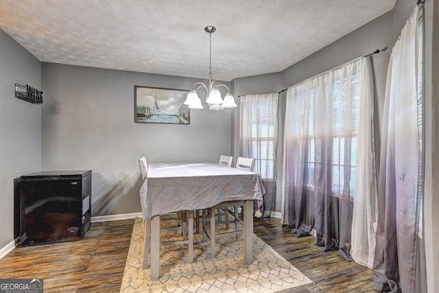 dining room with dark hardwood / wood-style flooring, a textured ceiling, and an inviting chandelier