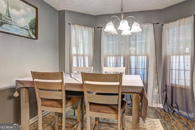 dining area featuring dark hardwood / wood-style flooring, a water view, a textured ceiling, and an inviting chandelier