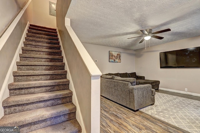 stairs with a textured ceiling, hardwood / wood-style flooring, and ceiling fan