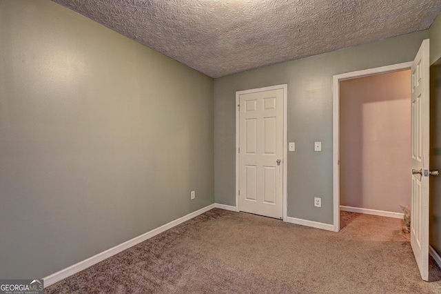 unfurnished bedroom featuring a textured ceiling and light carpet