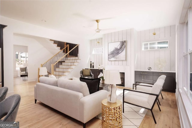 living room with ceiling fan, a fireplace, and light wood-type flooring