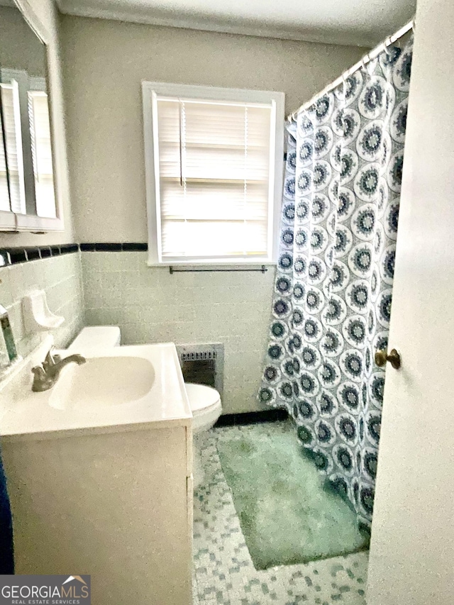 bathroom with vanity, toilet, and tile walls