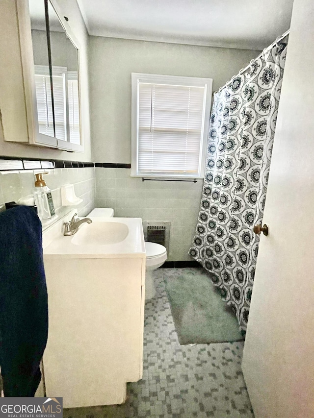 bathroom with vanity, tile walls, and toilet