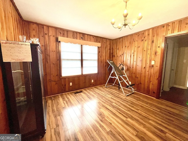 interior space with a notable chandelier, wood-type flooring, and wooden walls