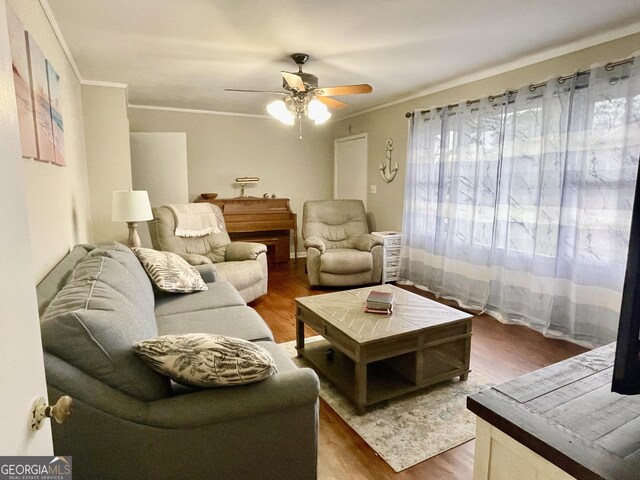 living room with hardwood / wood-style flooring, ceiling fan, and ornamental molding