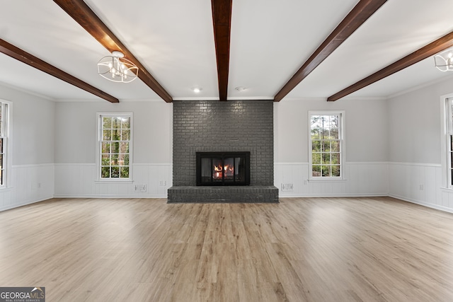 unfurnished living room featuring a fireplace, light wood-type flooring, and an inviting chandelier