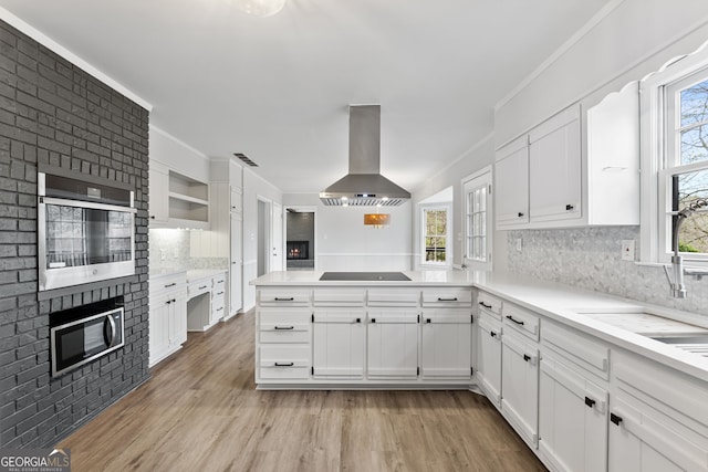 kitchen featuring a healthy amount of sunlight, white cabinets, stainless steel appliances, and ventilation hood