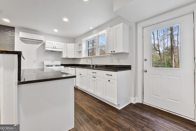 kitchen featuring sink, dark hardwood / wood-style floors, a wall mounted AC, white gas stove, and white cabinetry