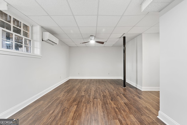 basement featuring an AC wall unit, a paneled ceiling, and dark hardwood / wood-style flooring