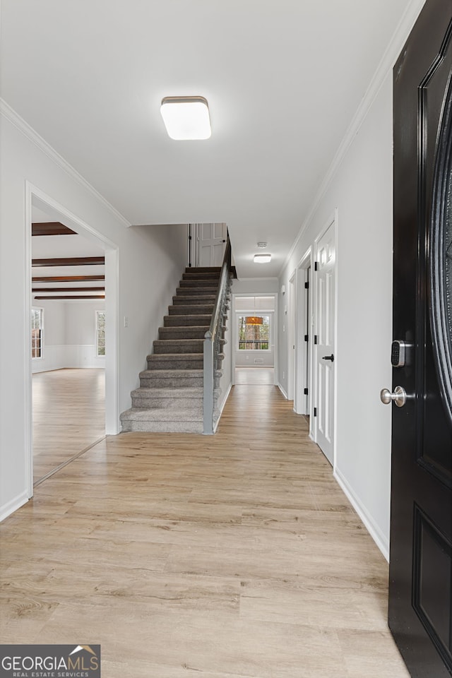 hallway with light hardwood / wood-style floors and ornamental molding