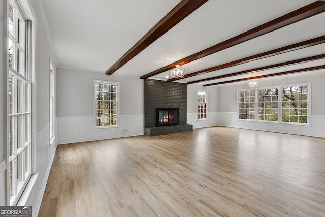 unfurnished living room featuring a notable chandelier, a healthy amount of sunlight, light hardwood / wood-style floors, and a fireplace