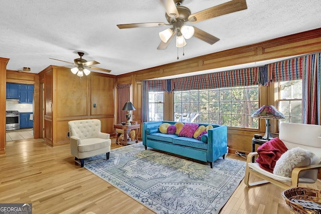 living room featuring a textured ceiling, light wood-type flooring, and ceiling fan