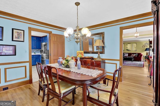 dining room featuring light wood-type flooring, an inviting chandelier, and crown molding