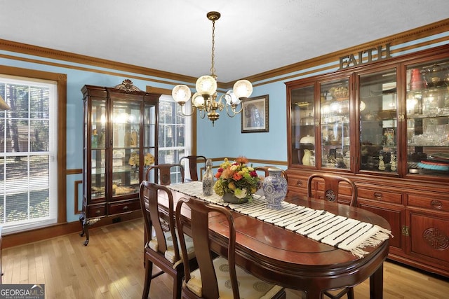 dining area featuring ornamental molding, light hardwood / wood-style flooring, a wealth of natural light, and an inviting chandelier