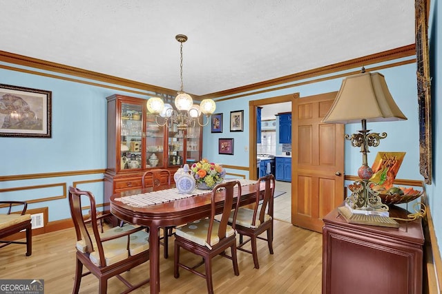 dining room featuring ornamental molding, a chandelier, and light hardwood / wood-style floors