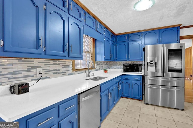 kitchen featuring blue cabinetry, sink, light tile patterned floors, and appliances with stainless steel finishes