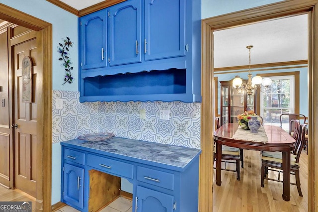 kitchen with an inviting chandelier, blue cabinets, crown molding, decorative backsplash, and decorative light fixtures