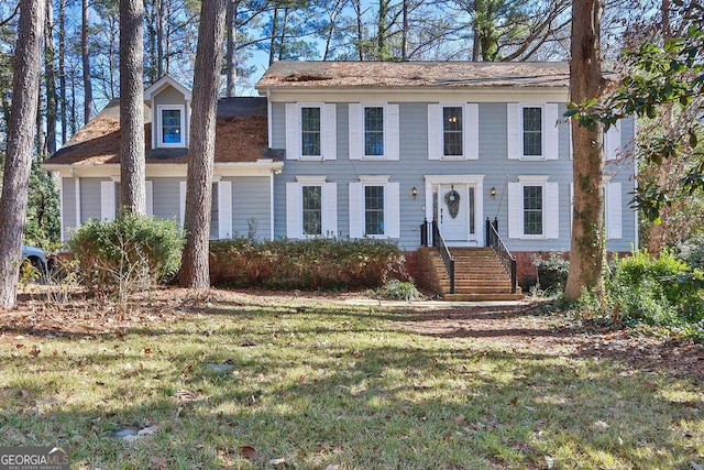 colonial-style house featuring a front lawn