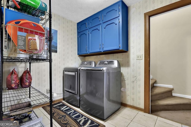 laundry room featuring washer and dryer, a textured ceiling, cabinets, and light tile patterned flooring