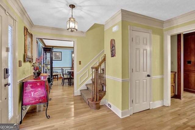 entryway with crown molding, light hardwood / wood-style floors, and an inviting chandelier