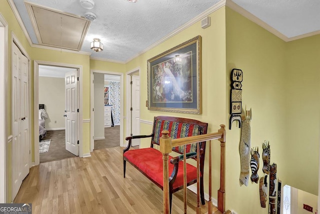 sitting room with crown molding, light hardwood / wood-style flooring, and a textured ceiling