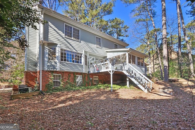 rear view of house featuring a wooden deck and a sunroom