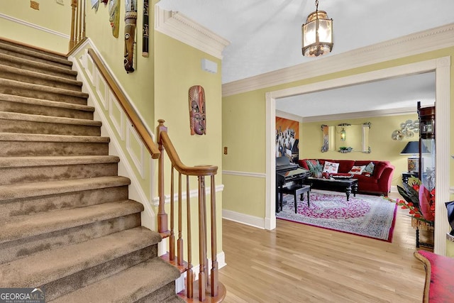 foyer entrance featuring hardwood / wood-style flooring, ornamental molding, and a chandelier