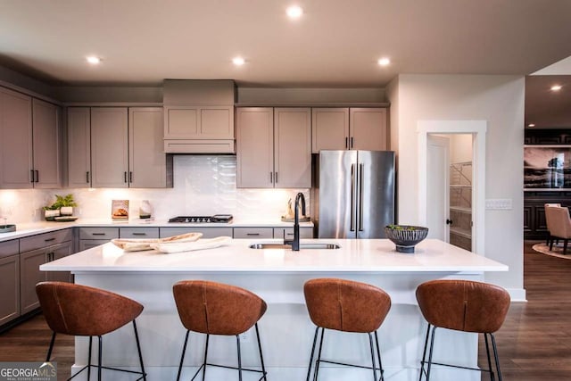 kitchen with sink, stainless steel appliances, gray cabinets, and an island with sink