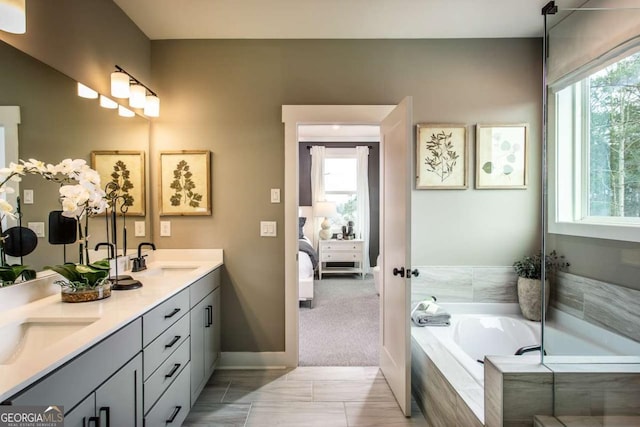 bathroom with vanity, a wealth of natural light, and tiled tub