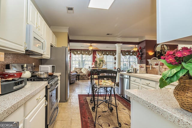 kitchen featuring backsplash, sink, crown molding, light tile patterned floors, and appliances with stainless steel finishes