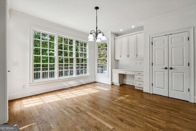 unfurnished dining area featuring an inviting chandelier, dark wood-type flooring, and crown molding