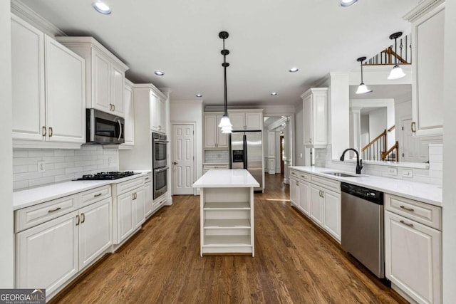 kitchen with sink, a center island, decorative light fixtures, and appliances with stainless steel finishes