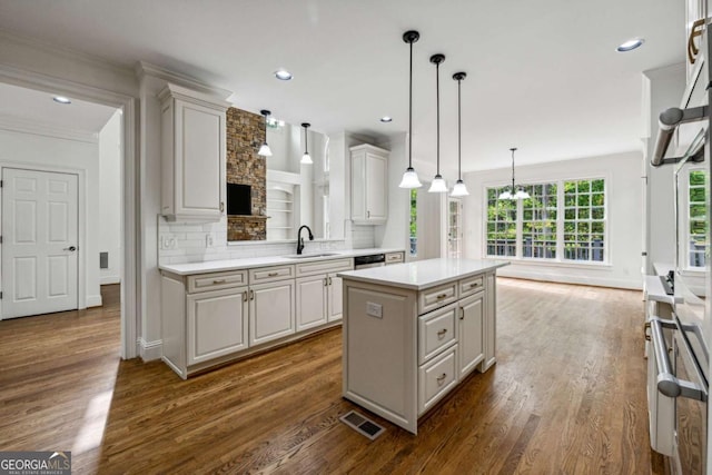 kitchen with backsplash, sink, white cabinets, a center island, and hanging light fixtures