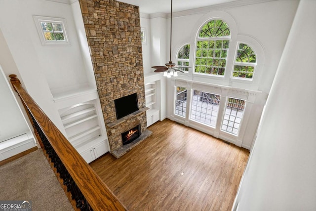 living room featuring built in shelves, ceiling fan, and a fireplace