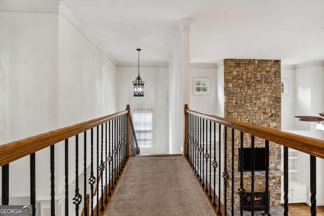 hall with carpet, a notable chandelier, built in features, and crown molding