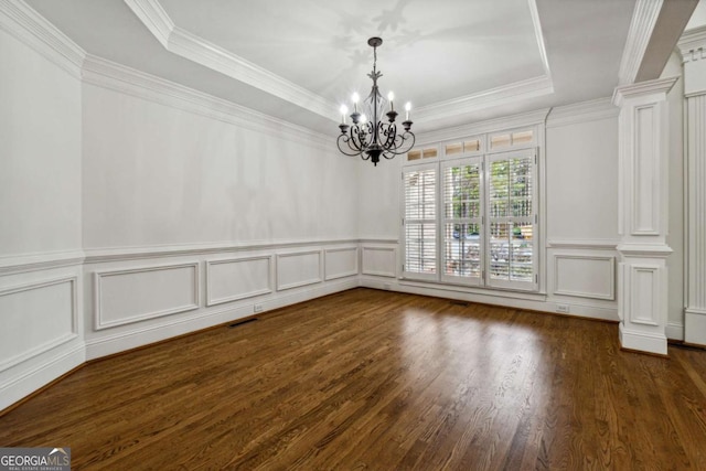 unfurnished room with dark wood-type flooring, decorative columns, a tray ceiling, and a notable chandelier