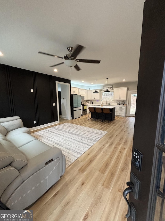 living room featuring ceiling fan and light hardwood / wood-style floors